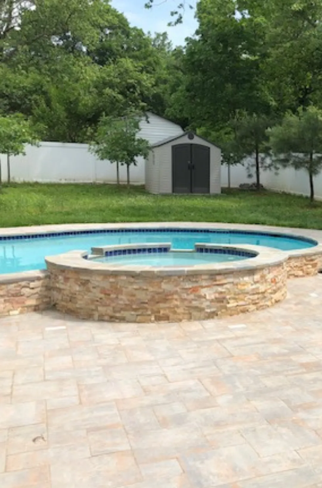 Swimming pool with a stone border connected to a circular pool, under renovation by Alpha Pool Renovations.