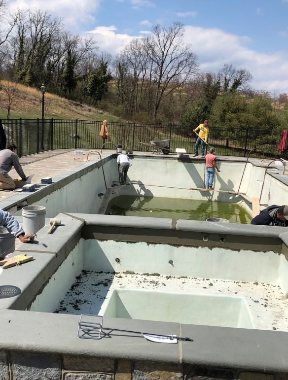 Pool resurfacing crew working inside a residential swimming pool in Northern Virginia